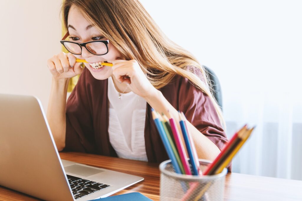 A girl biting a pencil while working